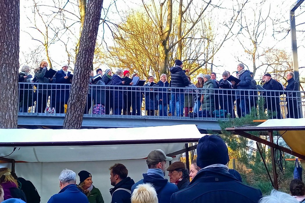 Menschen stehen auf einer Metallbrücke über dem Gemeindegelände