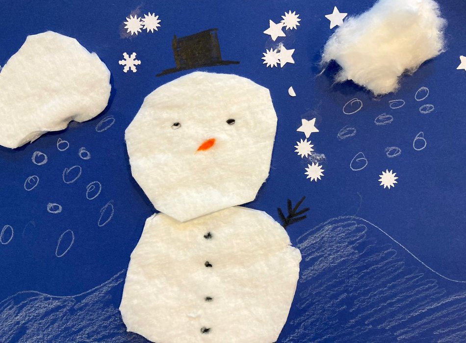 ein gebasteltes Bild von einem weißen Schneemann auf blauem Papier
