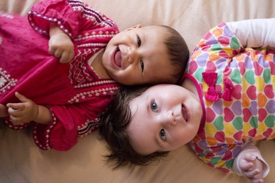 zwei kleine Kinder liegen auf dem Boden und lächeln