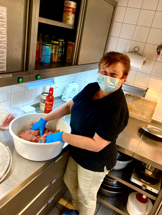 Die Köchin des Kindergartens steht in der Küche und bereitet in einer Schüssel Essen zu