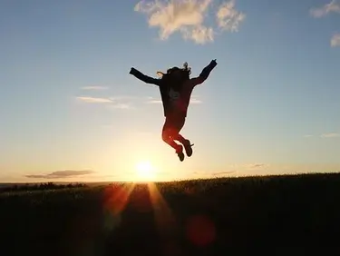 Ein Mensch springt in die Luft vor einem Sonnenuntergang im Hintergrund