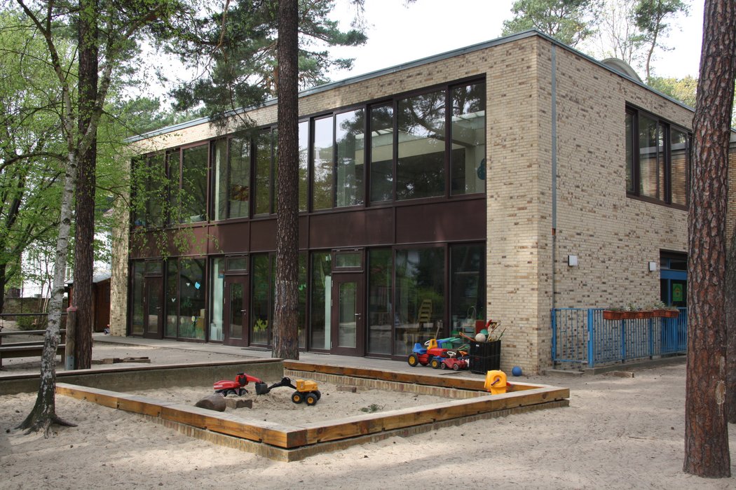 Das Gebäude des Kindergartens der Emmaus Gemeinde von draußen, im Vordergrund der Sandkasten