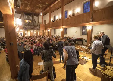 Menschen stehen und sitzen in der Kirche während eines Gottesdienstes, aus Sicht des Altars