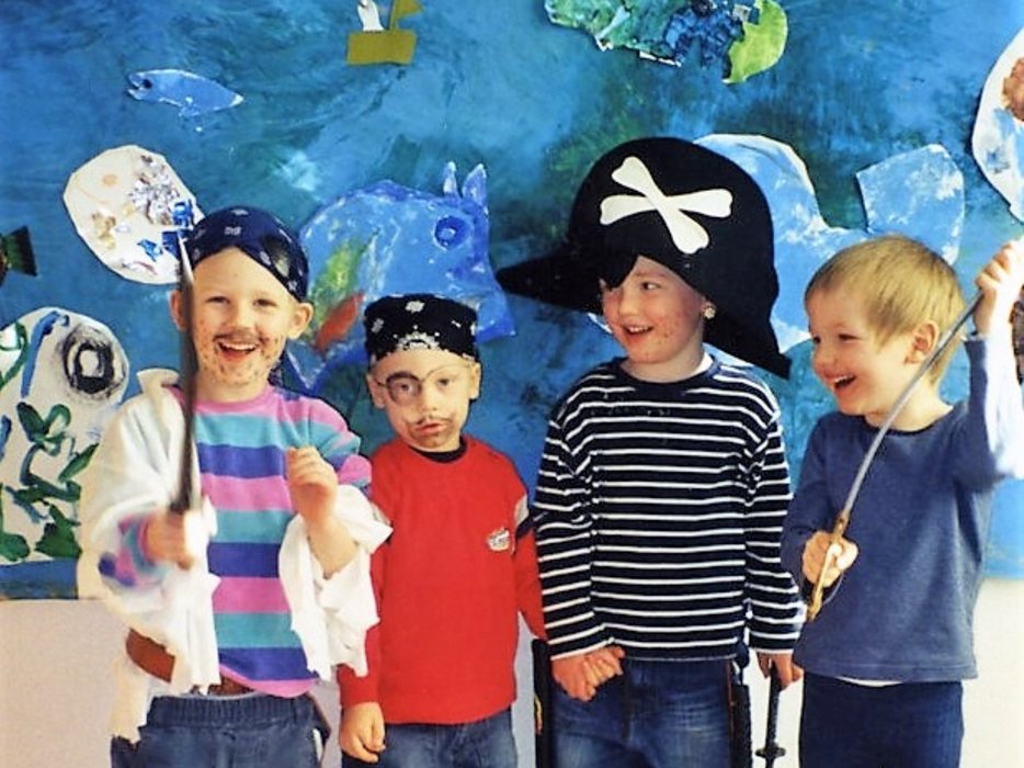 vier Kinder, die verkleidet sind und vor einem blauen Hintergrund stehen