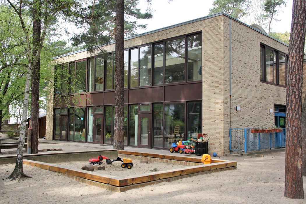 Das Gebäude des Kindergartens von außen, im Vordergrund ein Sandkasten